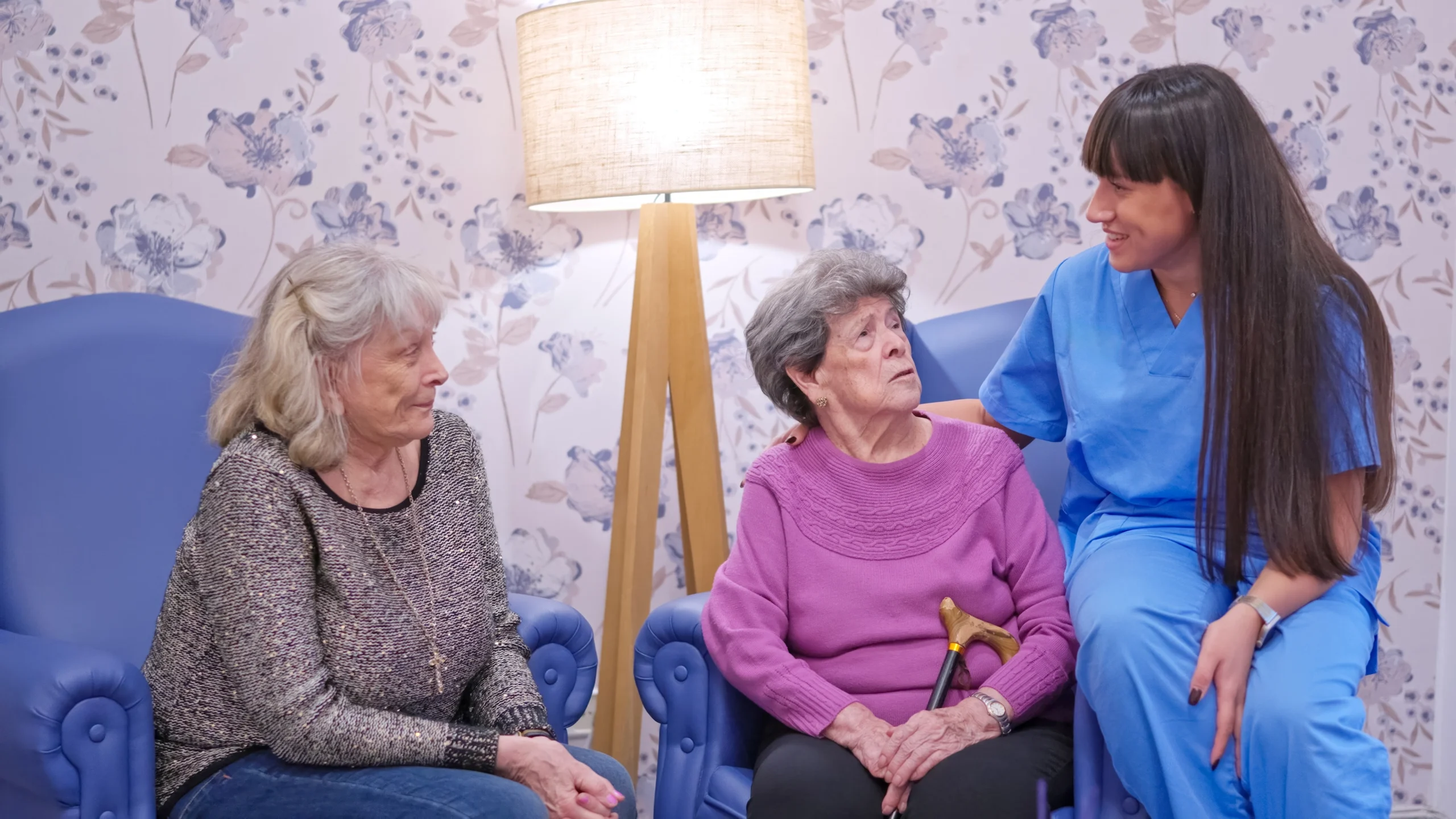 two dementia patients stare confused at kind nurse