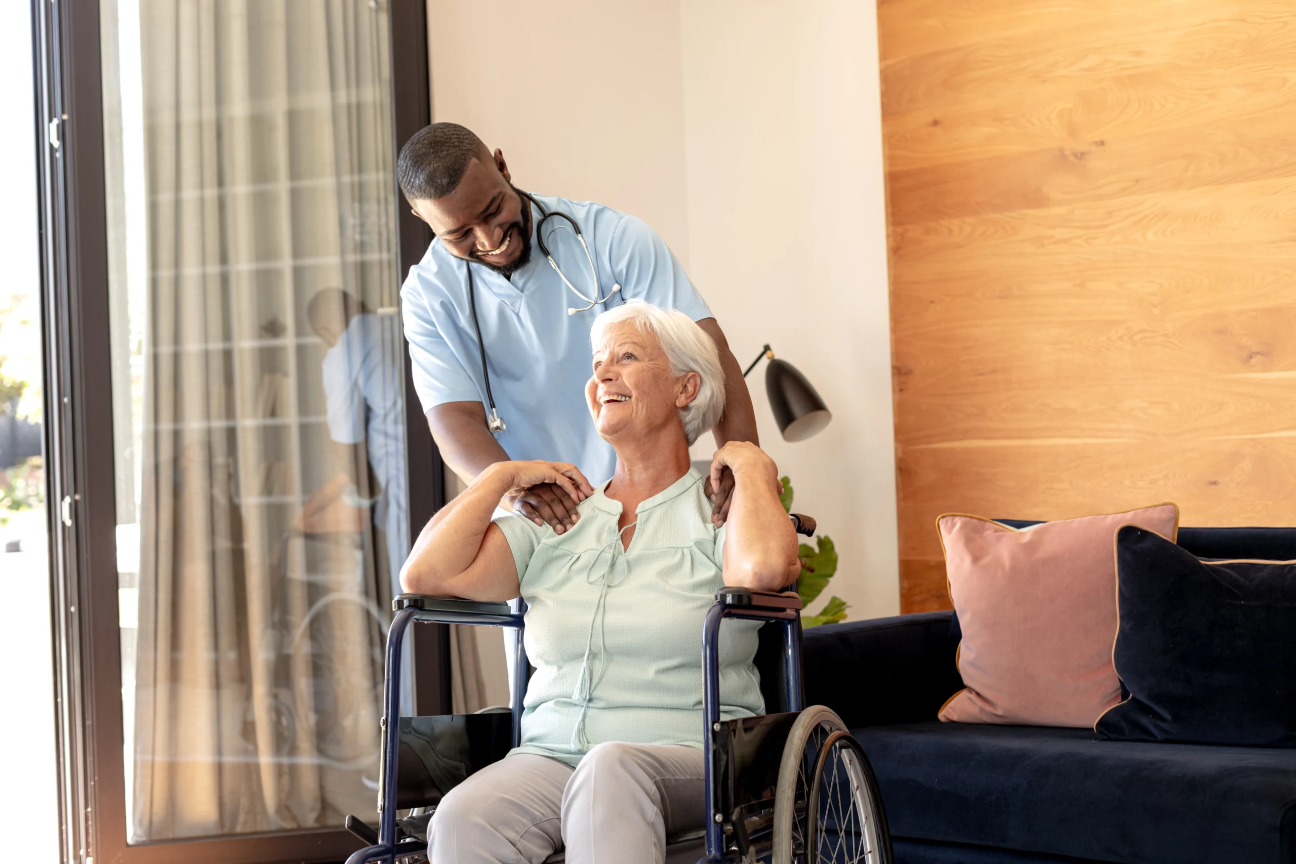 african nurse shares a laugh with senior woman in wheelchair