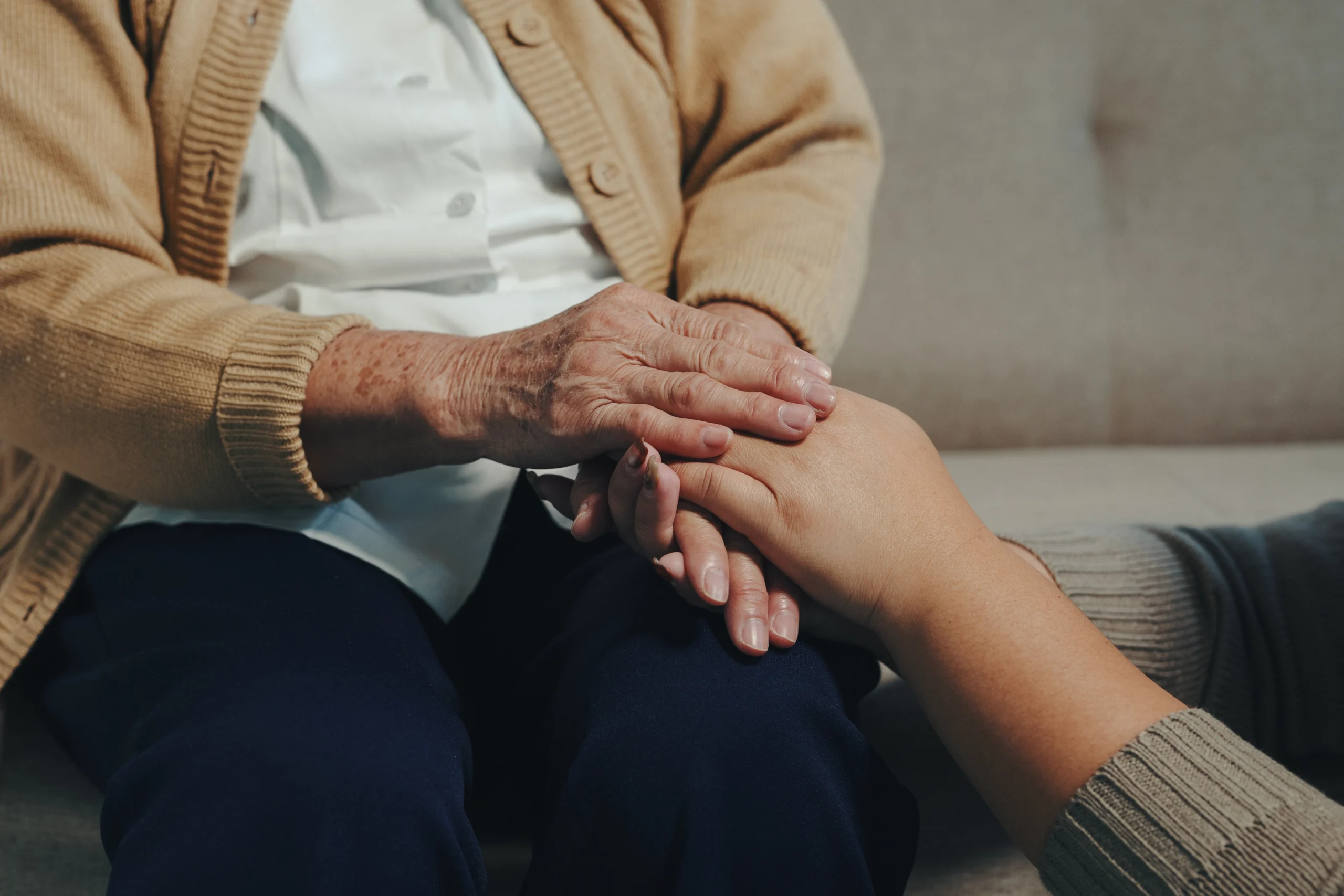 closeup of elderly person and young caregiver holding hands