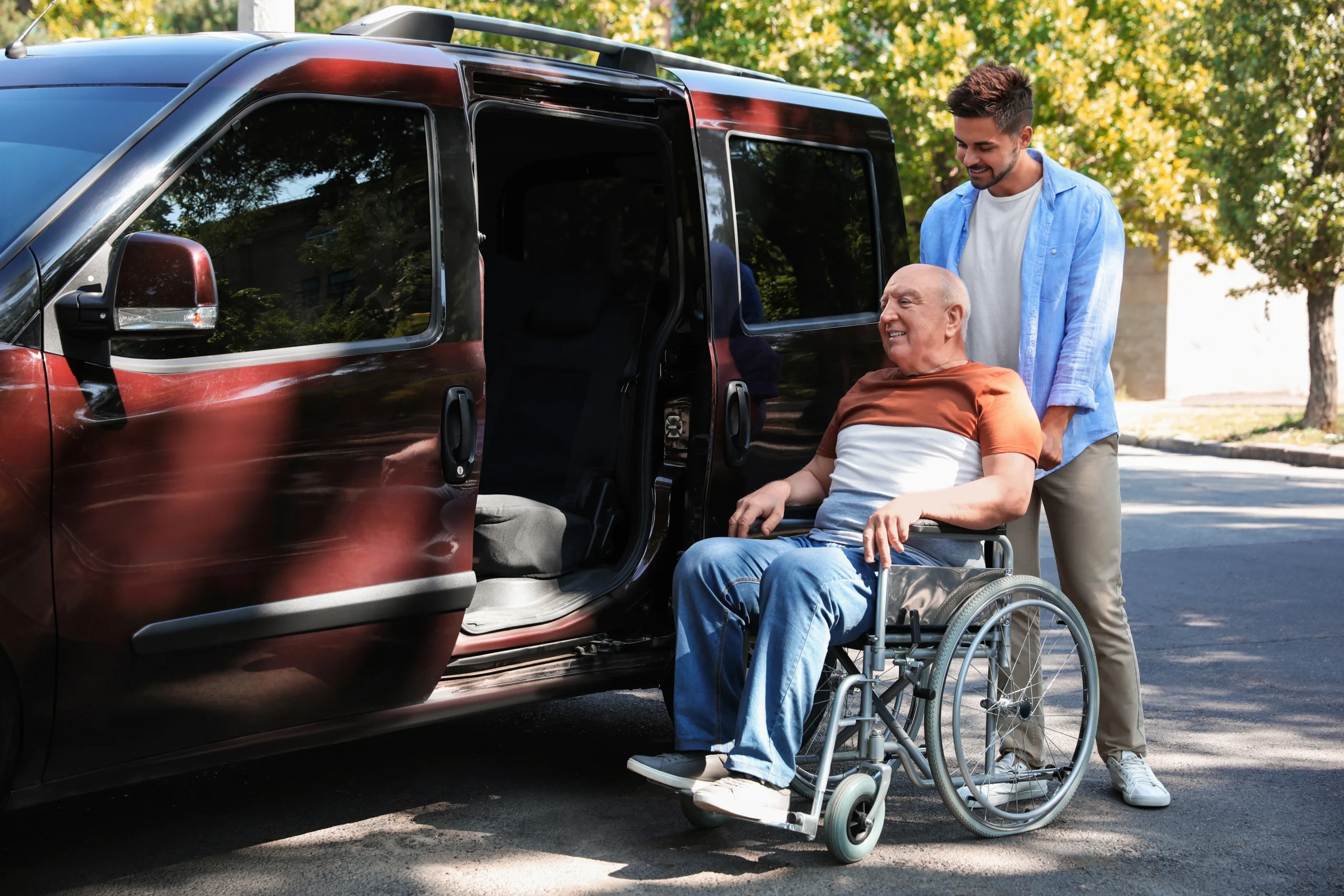young man helps elderly male get into a transport van